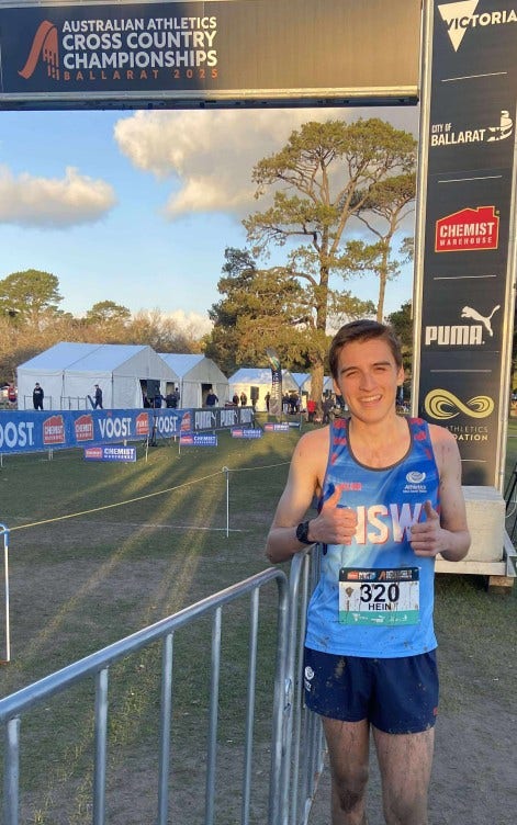 Photo of a competitor who is at the finish line of the cross country championships. He is smiling and giving thumbs up