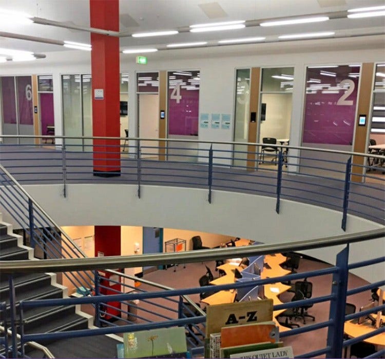 Photo of the upper level of the library looking down over the stairs to the desks on the lower level